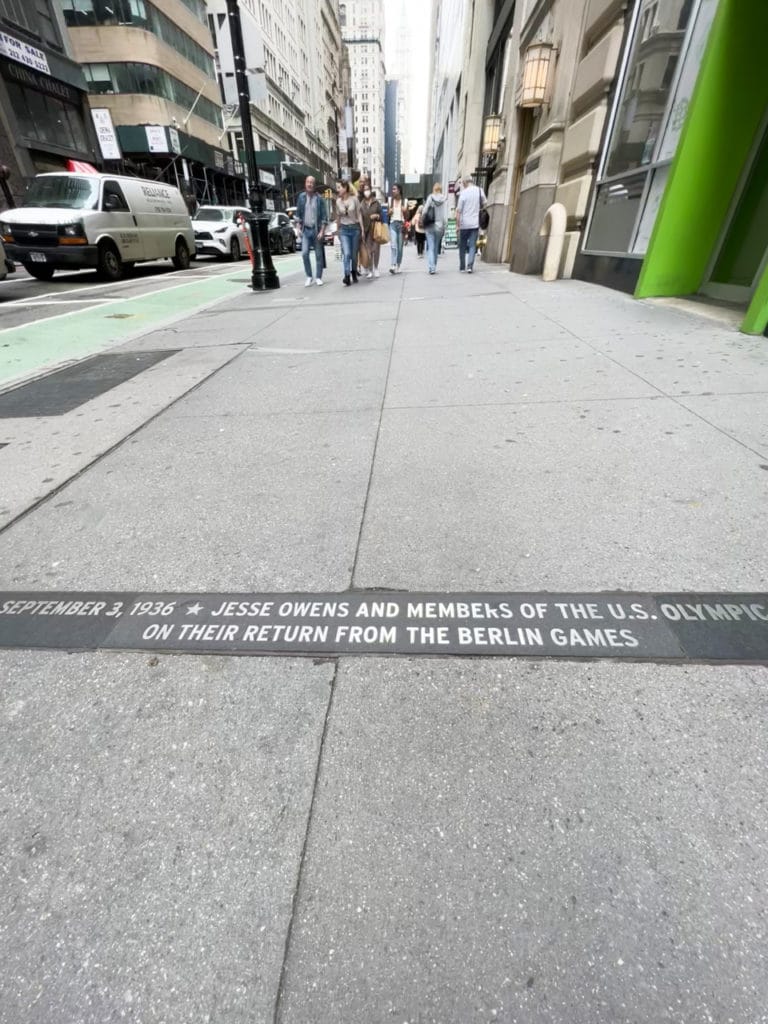 Sidewalk plaque that says September 3, 1936 Jesse Owens and Members of the U.S. Olympics on Their Return from the Berlin Games.