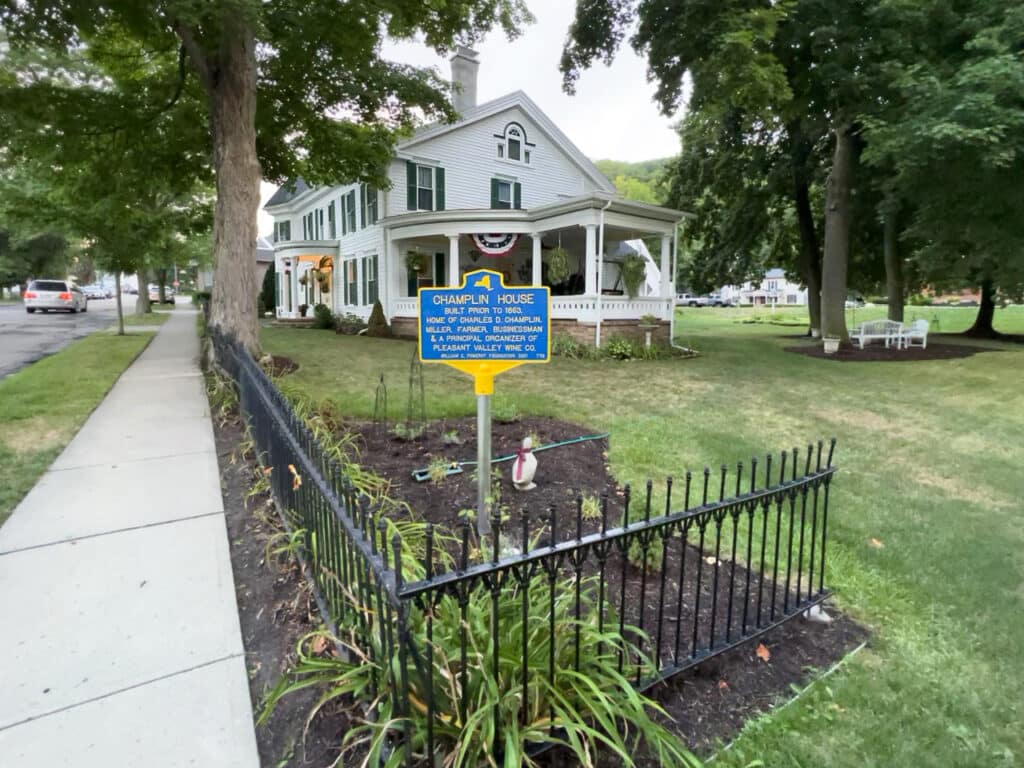 A blue historical marker in front of Champlin House in Hammondsport, NY.