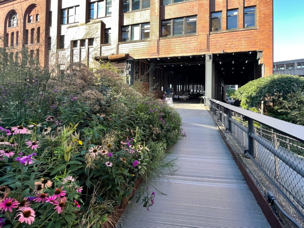 A flower-lined path leading to a semi-enclosed passageway on the High Line in New York City.