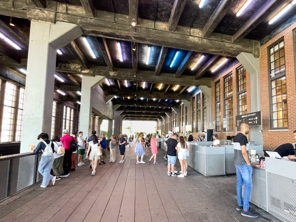 A semi-enclosed passageway on the High Line in New York City, with vendors selling food, coffee, and souvenirs.