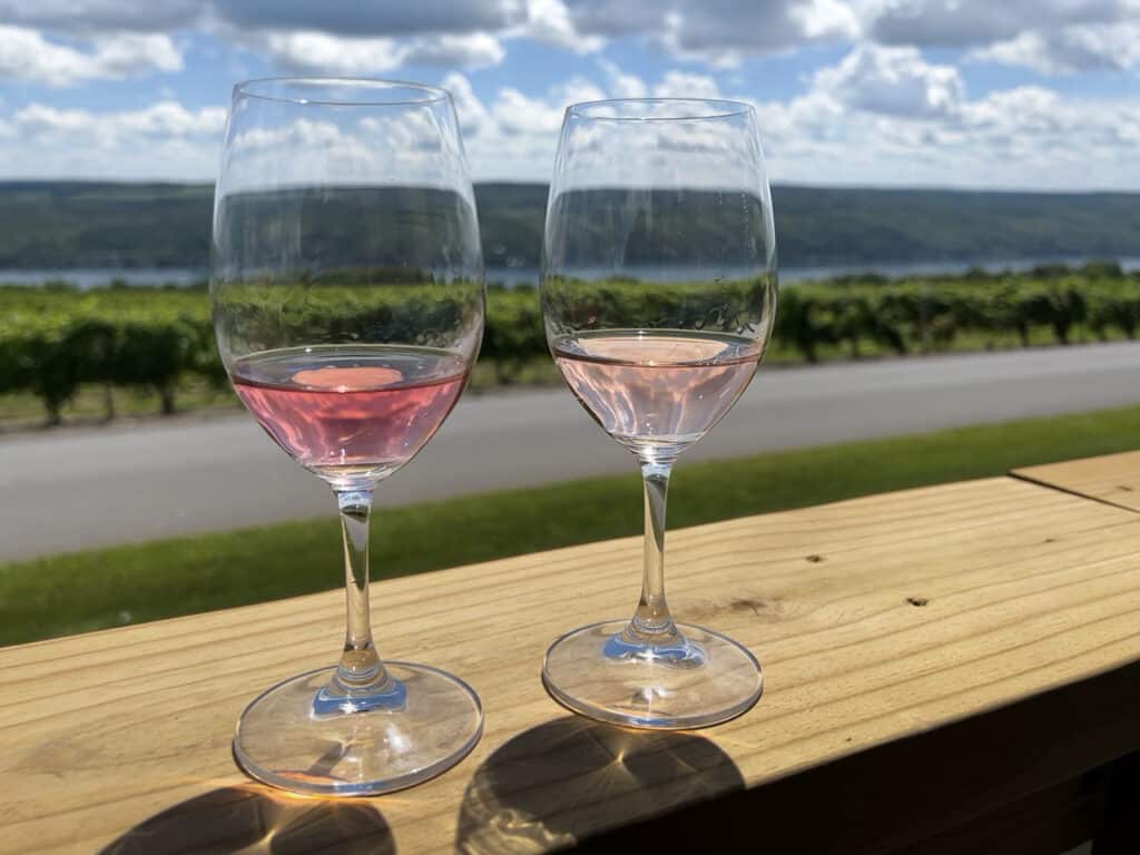Two glasses of rose wine on a railing overlooking Keuka Lake in the Finger Lake, NY.