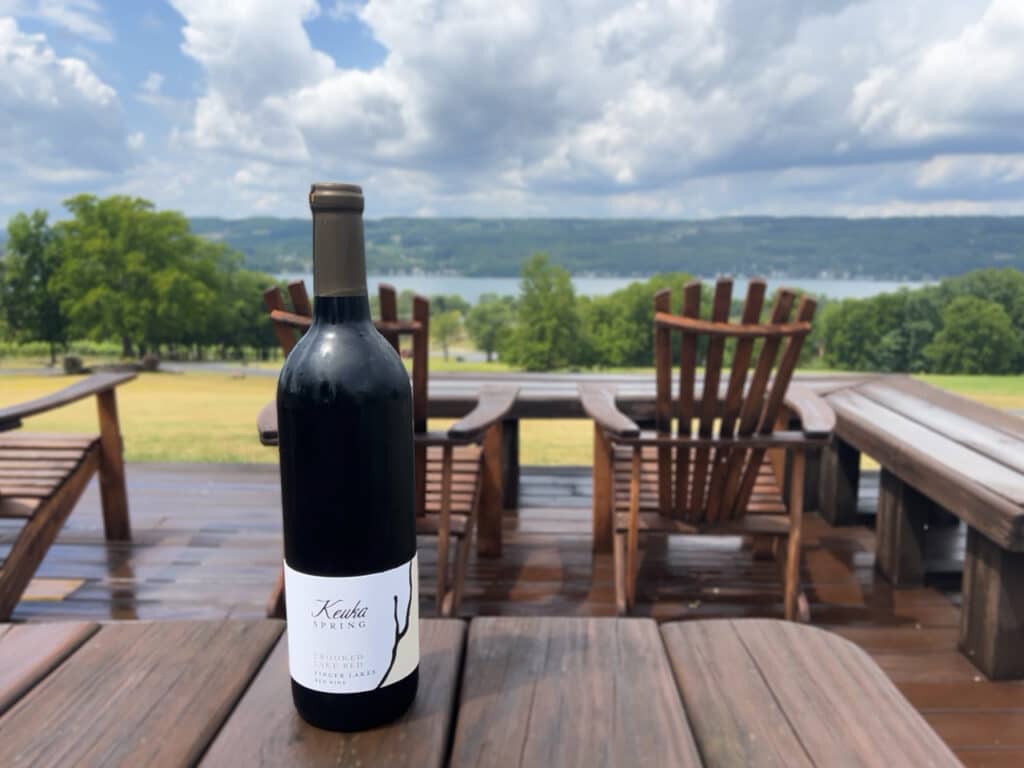 A bottle of red wine sitting on a table on a deck at Keuka Spring Vineyards in the Finger Lakes, NY.