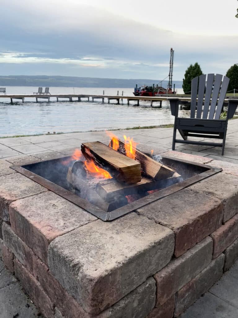 An outdoor fire pit with a dock and Seneca Lake in the background in the Finger Lakes, NY.