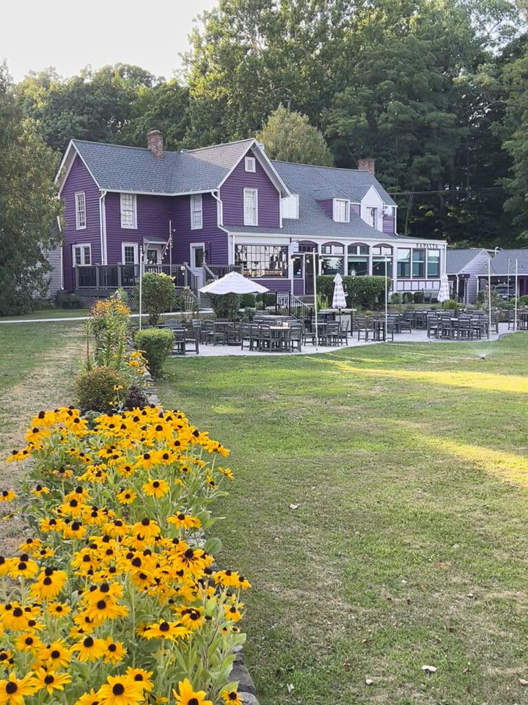 A flower garden in front of the purple exterior of Plum Point Lodge on Seneca Lake in the Finger Lakes, NY.
