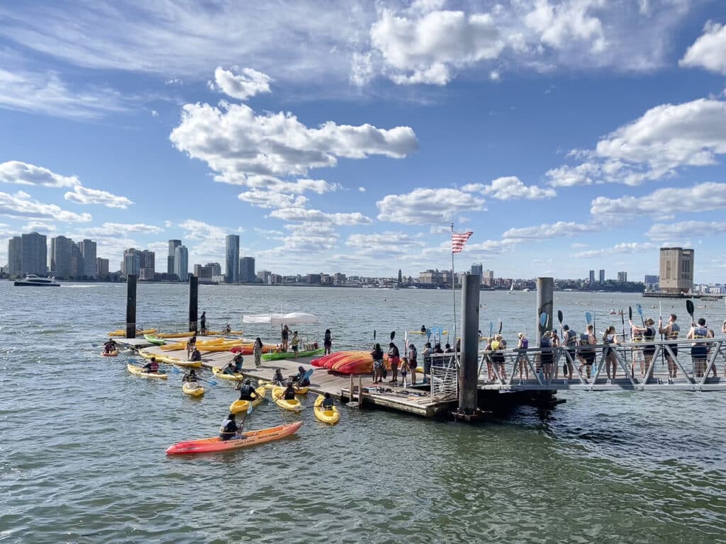 Several kayakers near a pier in the Hudson River in New York City. 