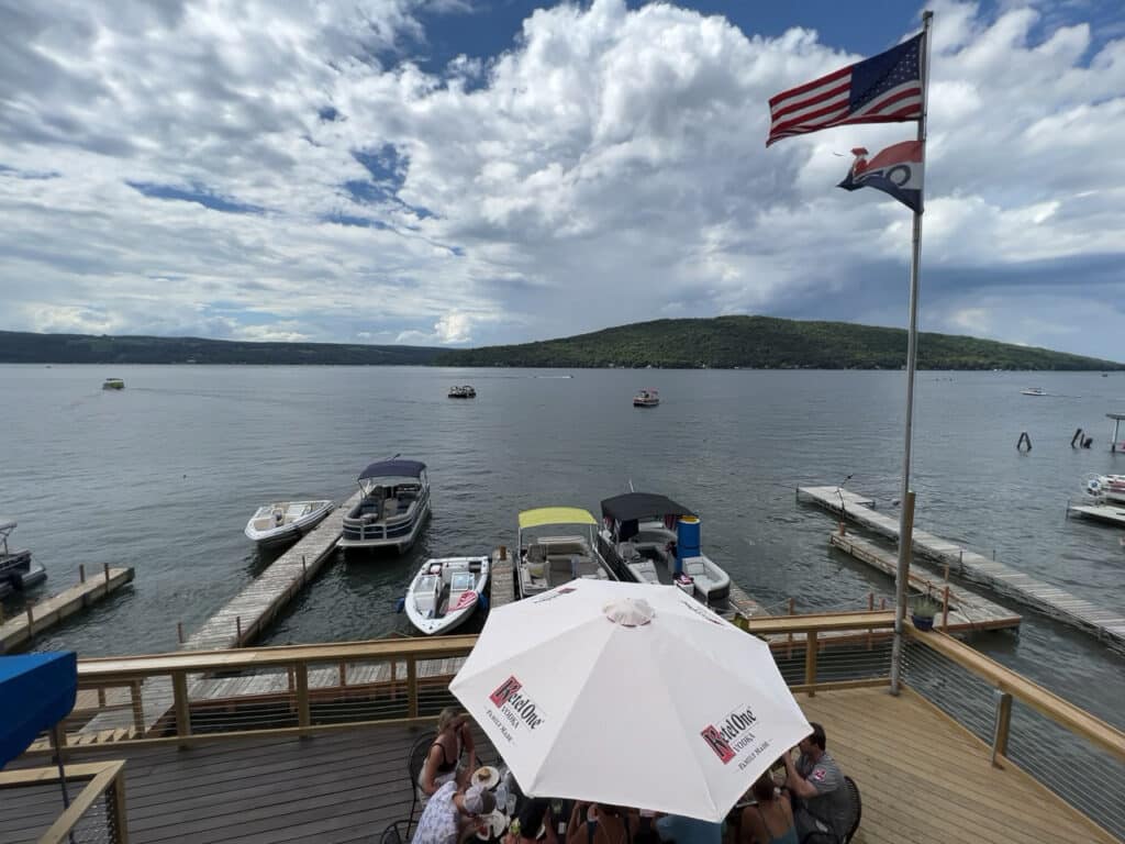 A group of people dining on the deck of a restaurant that overlooks Keuka Lake in Hammondsport, NY.