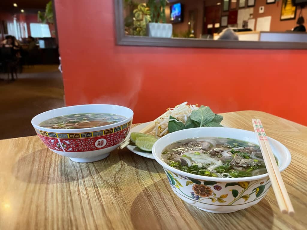 Two bowls of Pho Vietnamese soup on a table at a restaurant. 