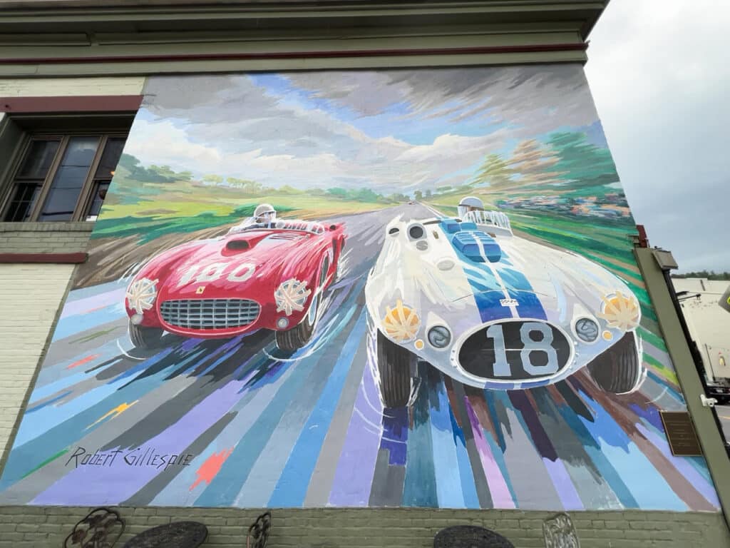 An outdoor mural of two race cars on a building in Watkins Glen, NY.