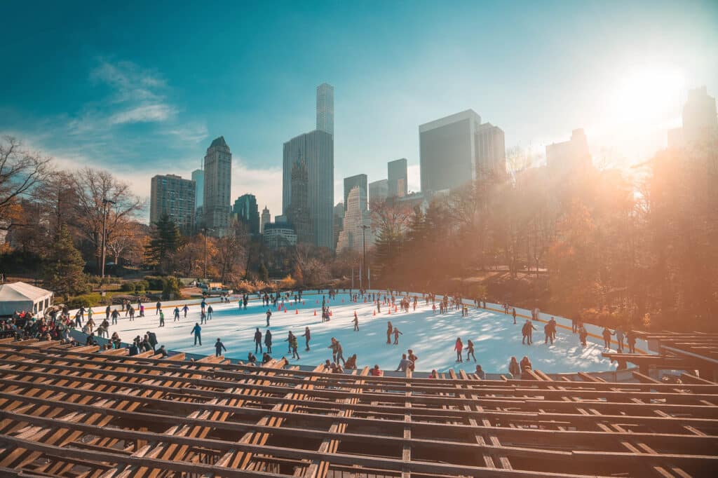 Several people ice skating at Wollman Rink in Central Park in New York City.