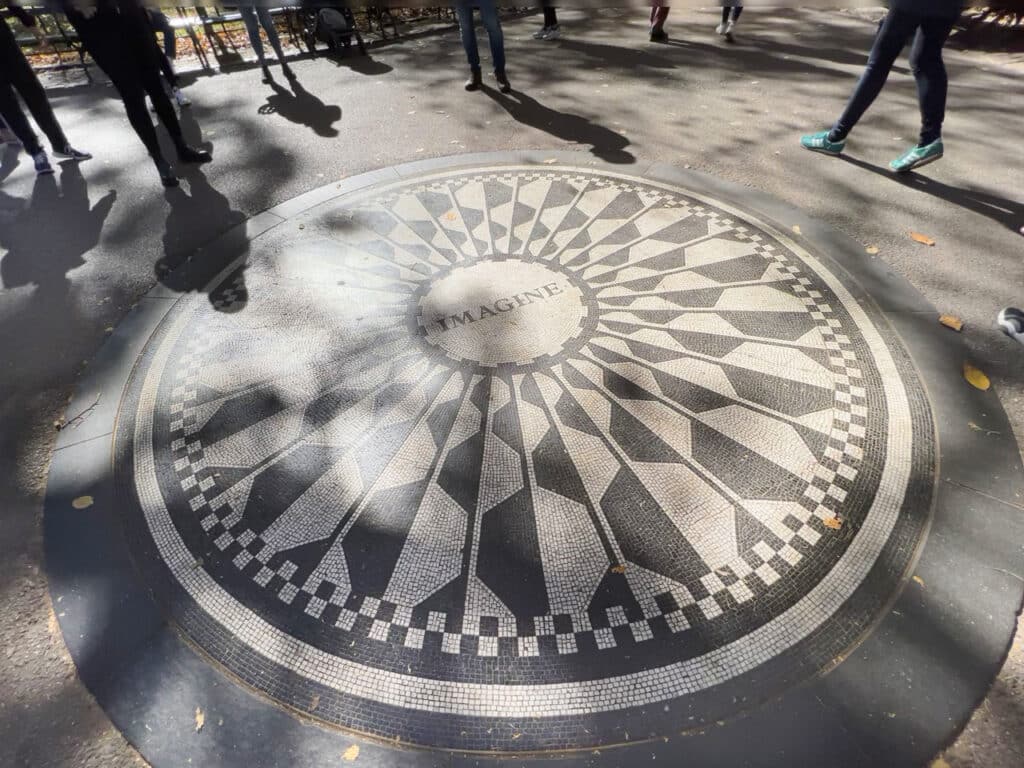 A gray and white mosaic with the word Imagine at the center, located in Central Park in New York City. 