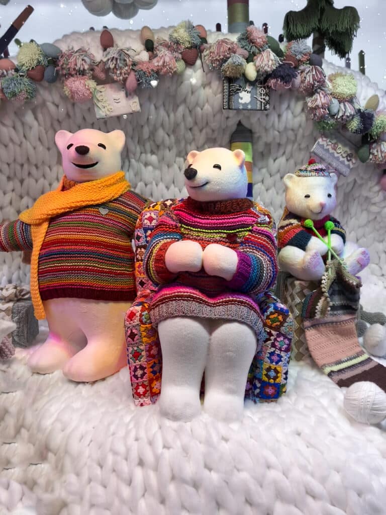 Three stuffed polar bears wearing sweaters in a Christmas window display at Macy's in New York City.