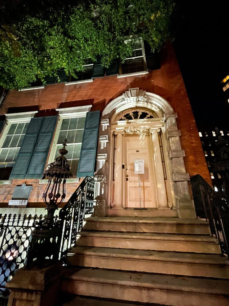 The steps and front door of a 19th century mansion in New York City at night. 