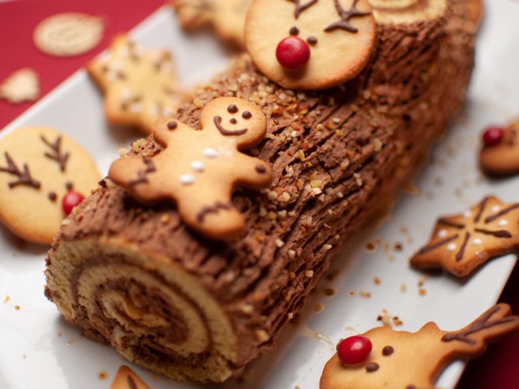 Chocolate Yule log decorated with cookies in the shape of a gingerbread man and a reindeer. 