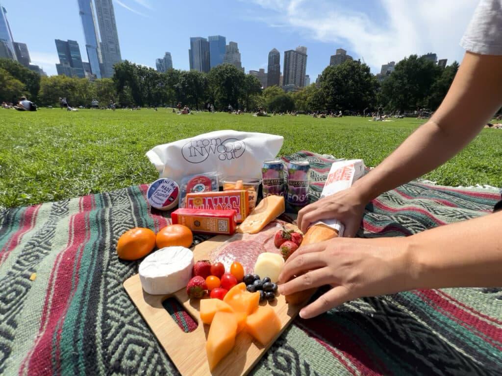 Fruit, cheese, and chocolates arranged on a blanket for a picnic in Central Park in New York City.