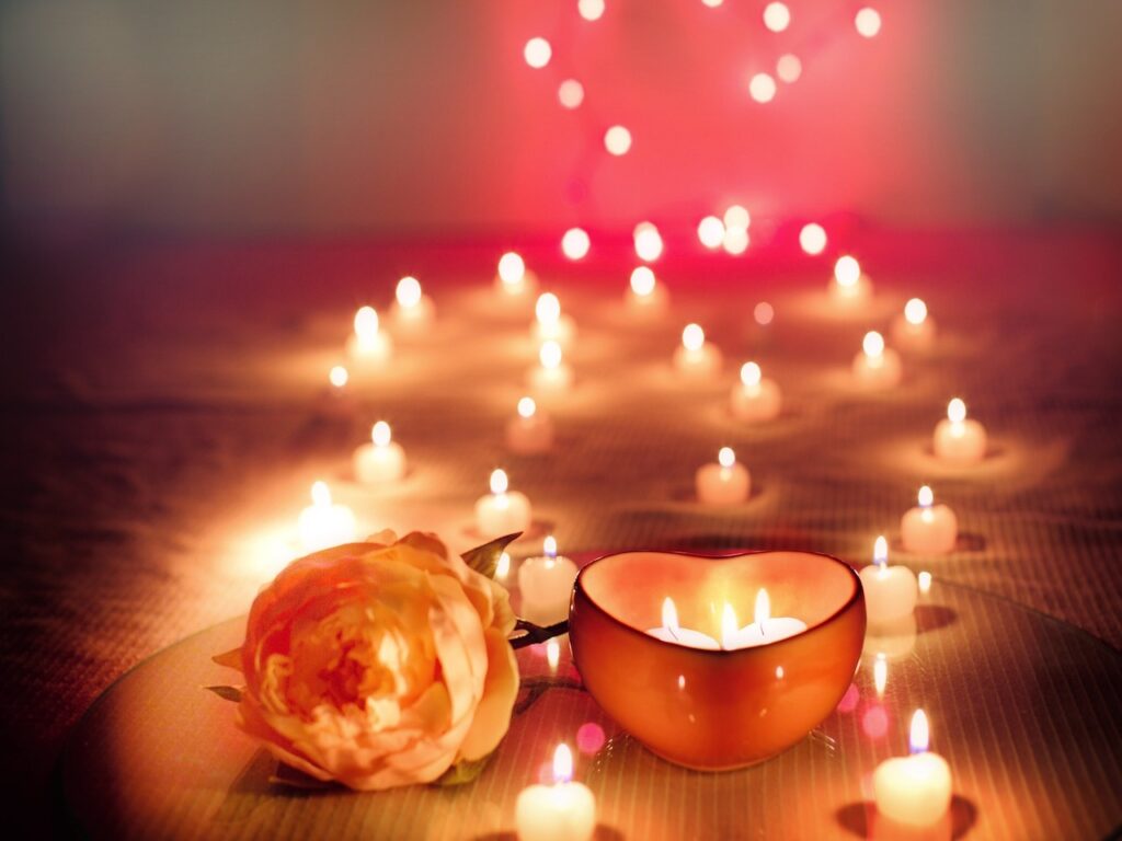 A rose, a heart-shaped candle, and several lit tea candles.