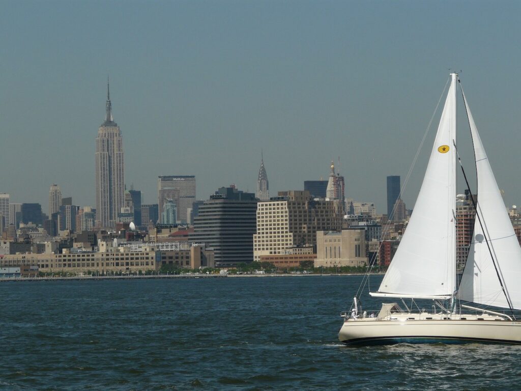 A sailboat on the Hudson River. The New York City skyline is in the background.