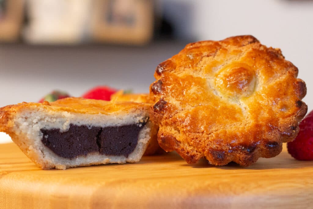 Two small Italian tarts called "pusties." One is cut in half to reveal a chocolate custard filling. 