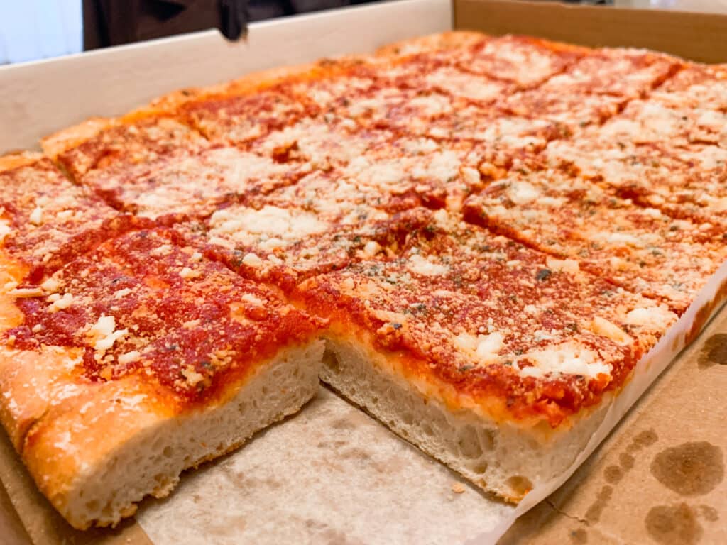 a whole tomato pie in a pizza box, with just one corner piece missing. 