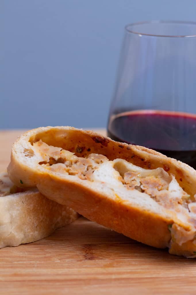 A slice of Italian sausage roll and a glass of red wine.