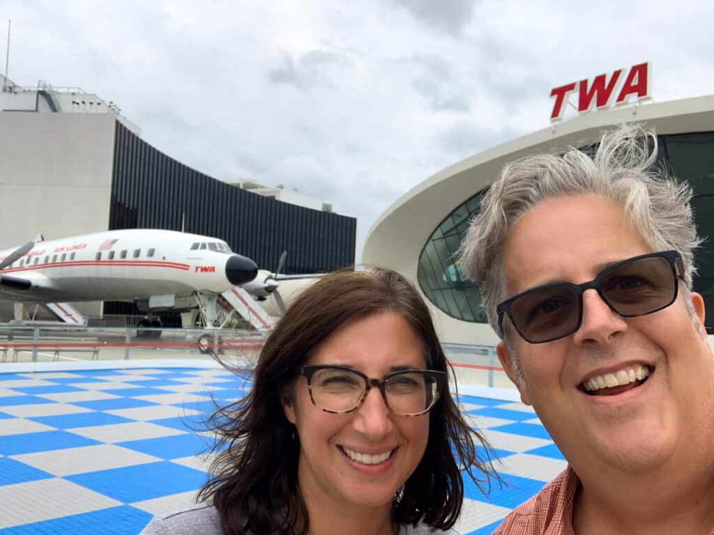 A man and a woman posing outside of the TWA Hotel at JFK Airport in New York City.