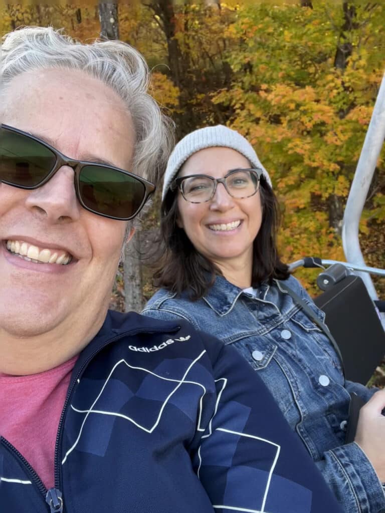A man and a woman posing as they ride a chairlift in the fall in Windham, NY. 