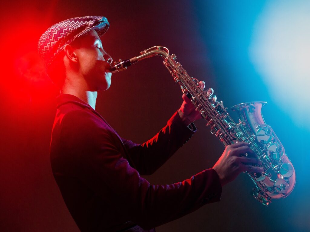 A man playing the saxophone with stage lights shining on him. 