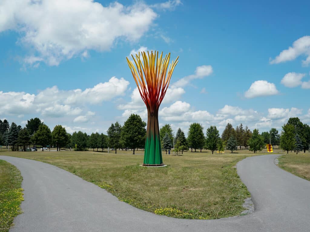 A large green, orange, and red sculpture at an outdoor sculpture park. 