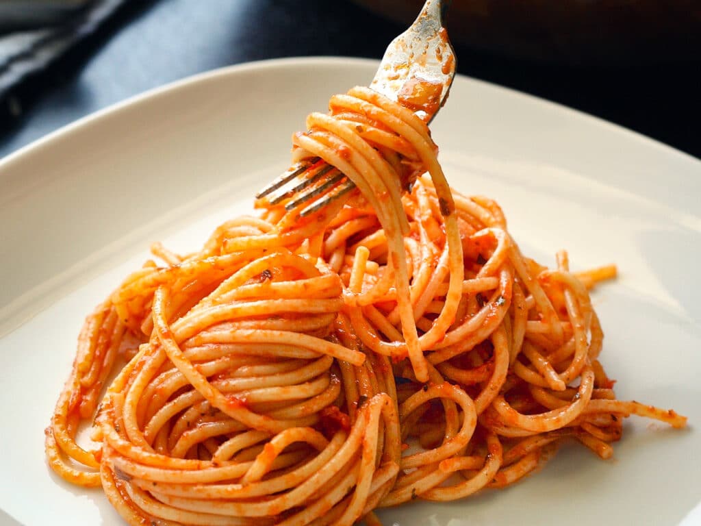 Serving of spaghetti with red sauce on a white dish.