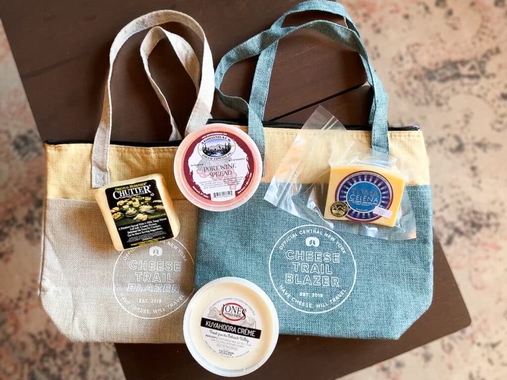Several kinds of cheese on top of two insulated totes that say "Official Central New York Cheese Trail Blazer"