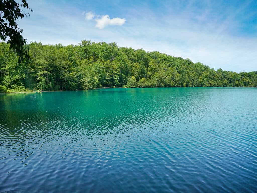 An aquamarine lake surrounded by trees.
