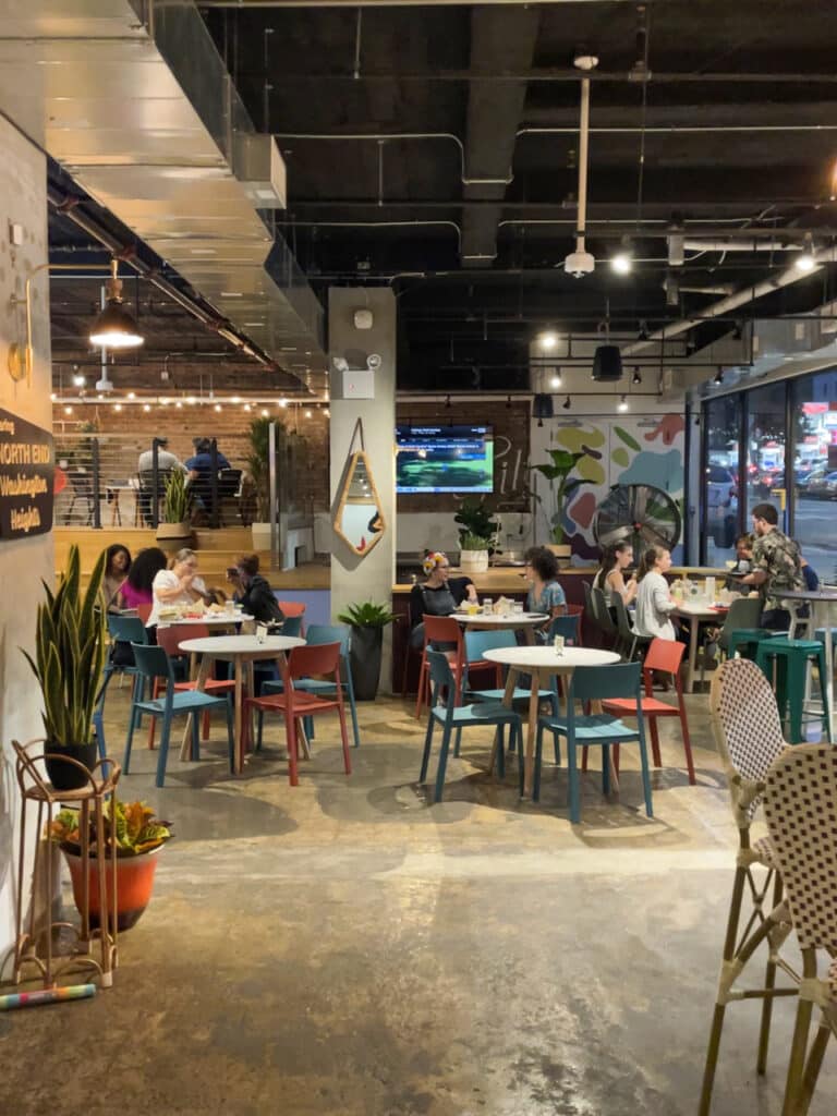 People sitting at cafe tables inside a food hall.
