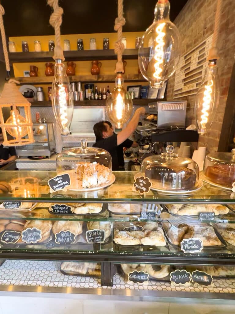 A man working behind a glass display case full of pastries in a cafe. 