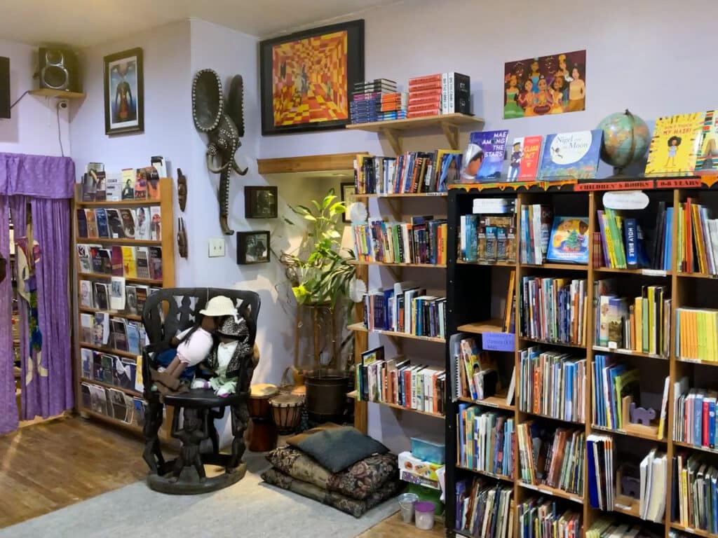 Bookshelves surrounded by posters, wall hangings, and pillows inside a bookstore. 