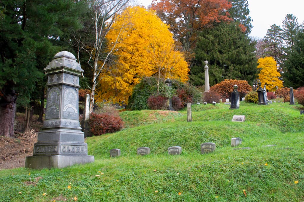 A cemetery in Owego, NY surrounded by trees in bright autumn colors. 
