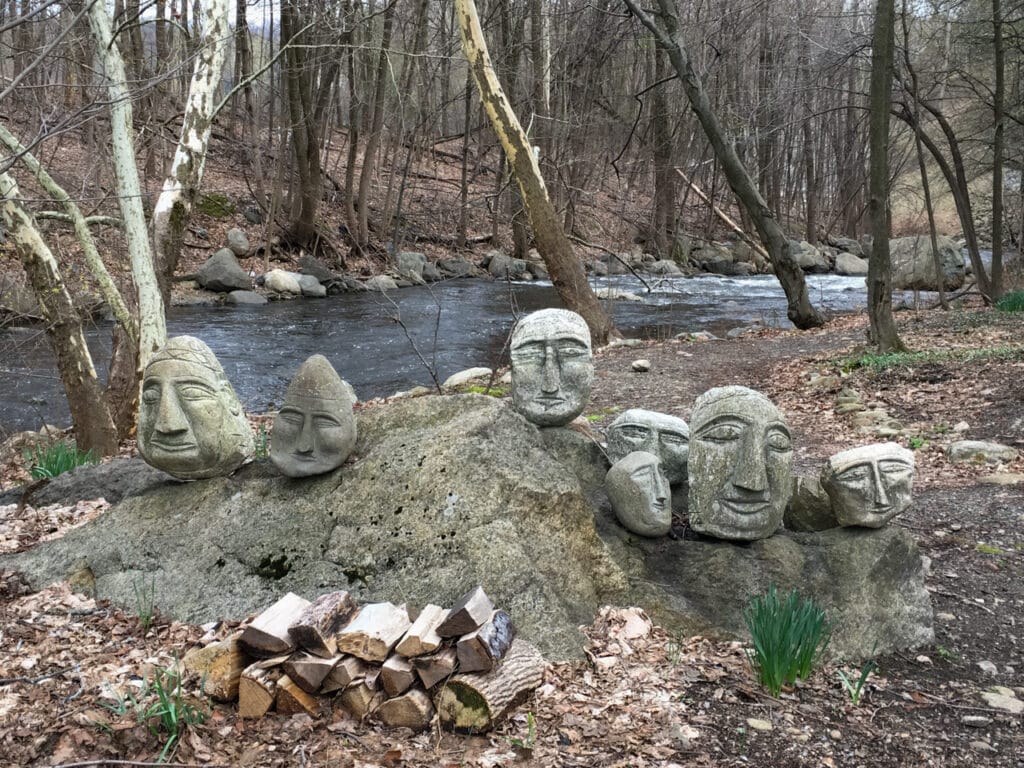 Row of large stones that all have whimsical faces carved into them.