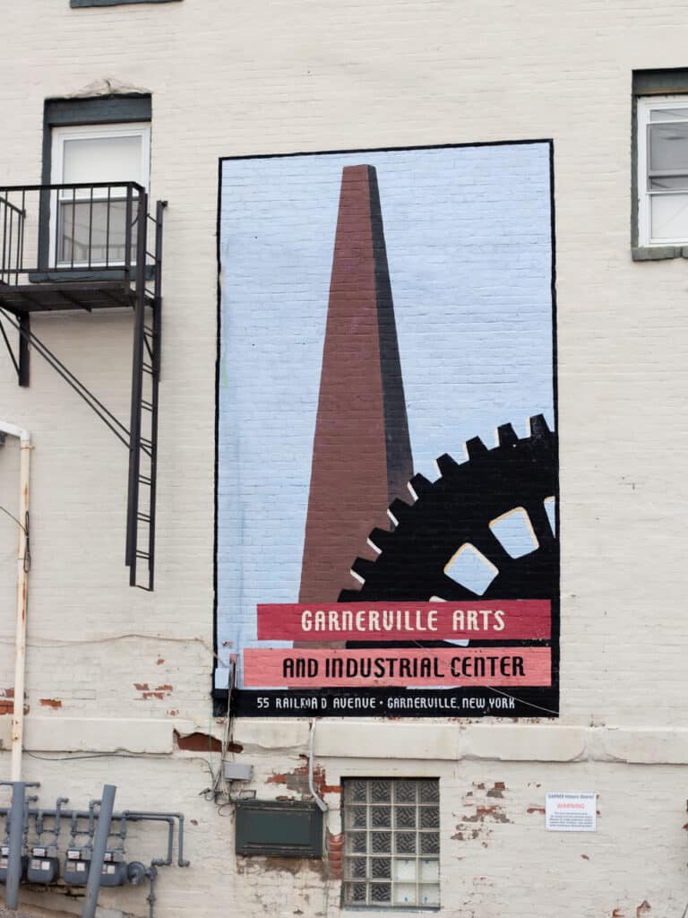 A mural on an outside wall that has a painting of a smokestack and says Garnerville Arts and Industrial Center.