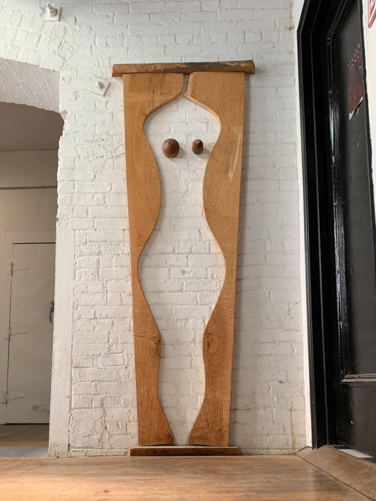 A piece of art that consists of  woman's silhouette carved out of a piece of wood.