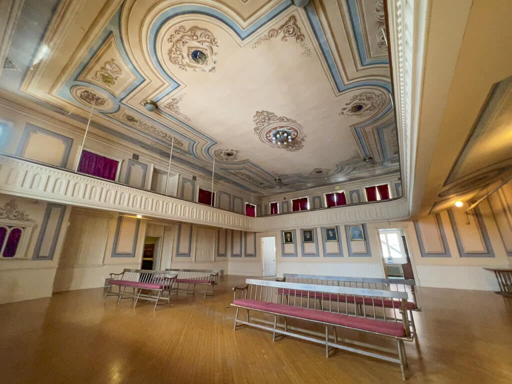 A large room with benches and an elaborately painted ceiling.