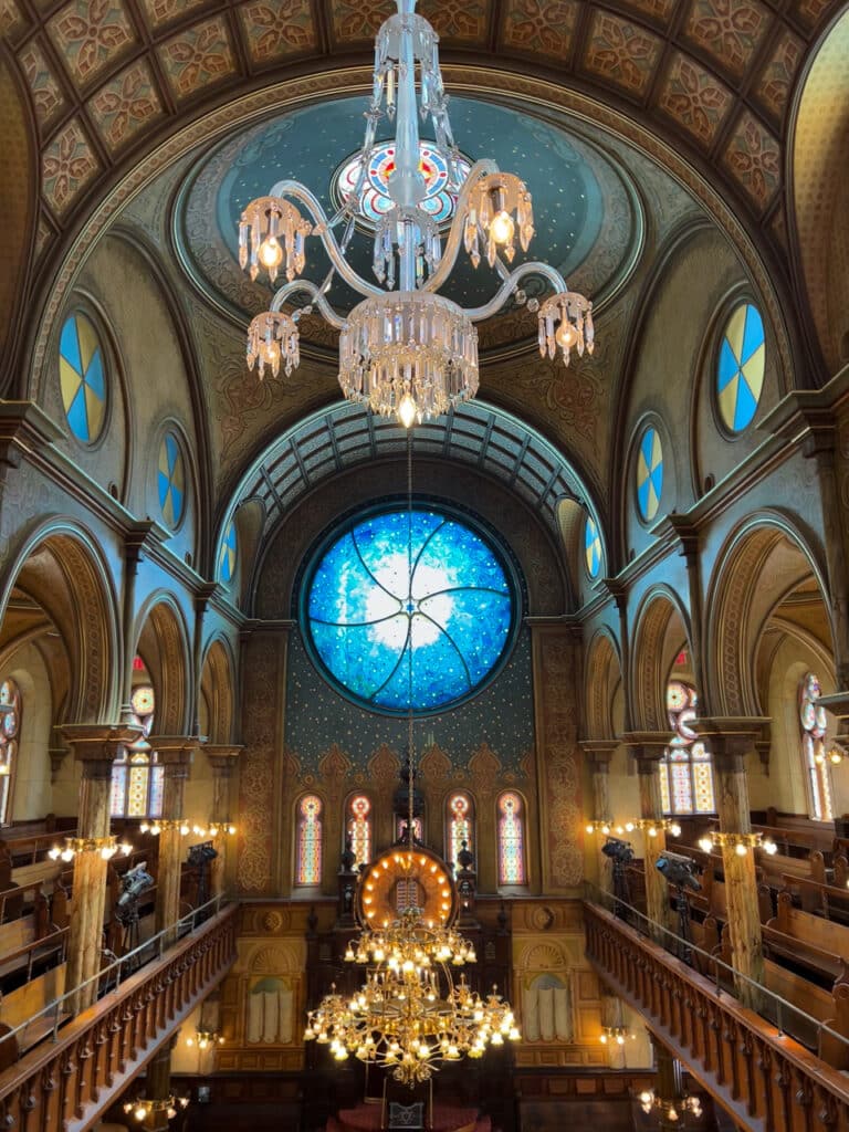A large, round, blue stained-glass window in a synagogue.