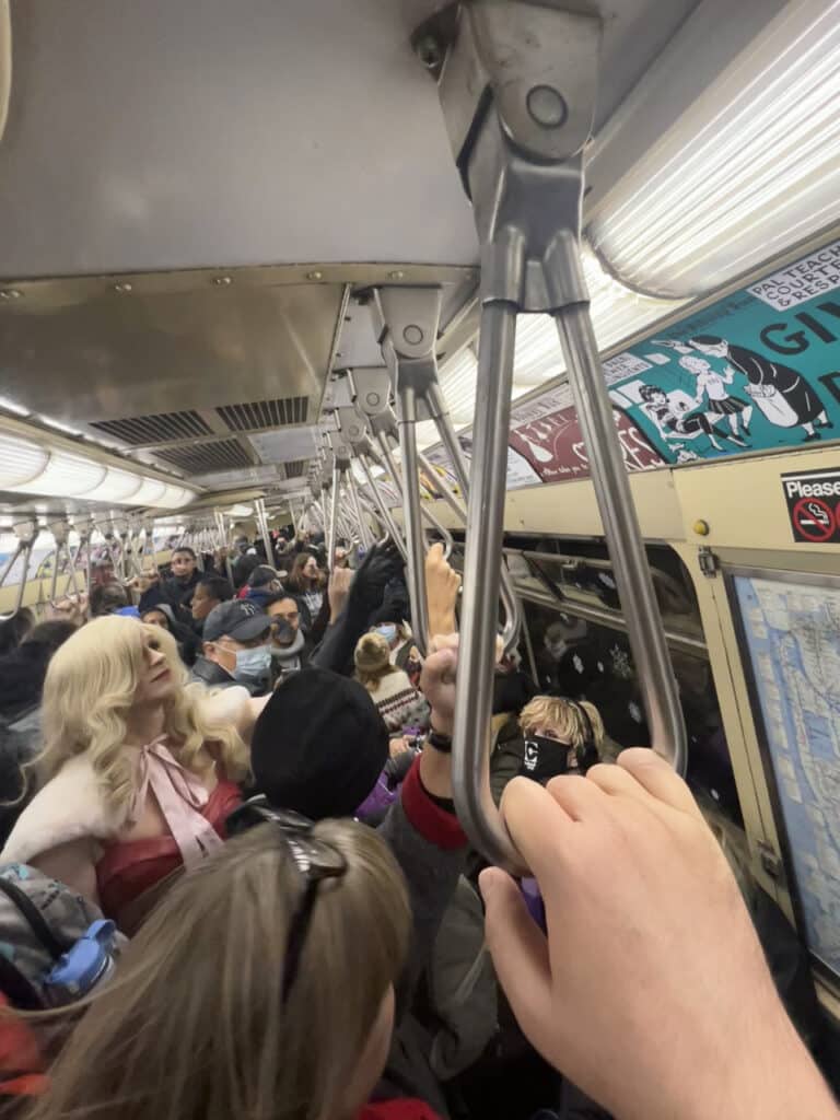 Inside a crowded, old-fashioned New York City subway car.