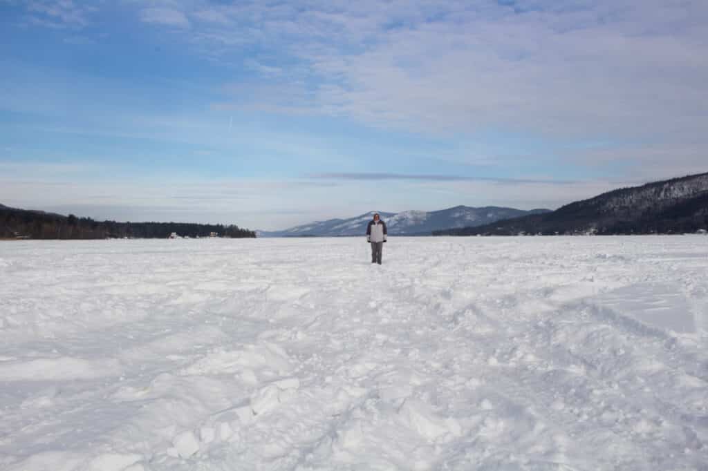 A person in the distance standing on frozen, snow-covered Lake George in Lake George, NY.
