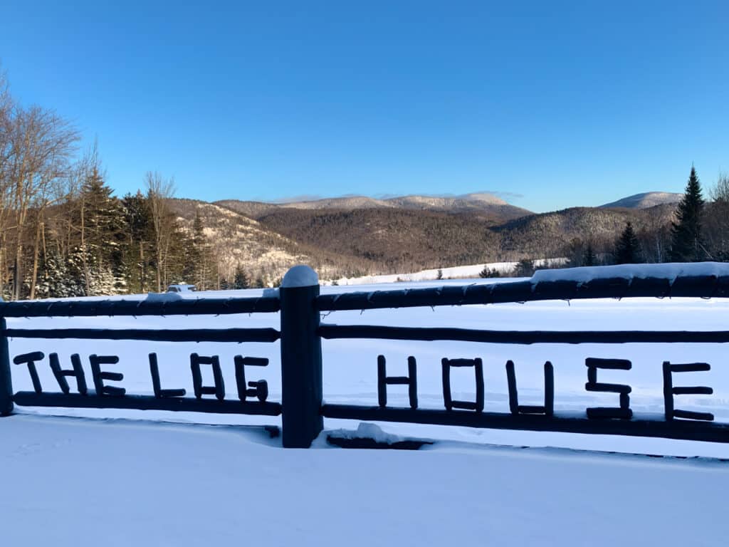 A rustic sign made of logs that spell out "The Log House"