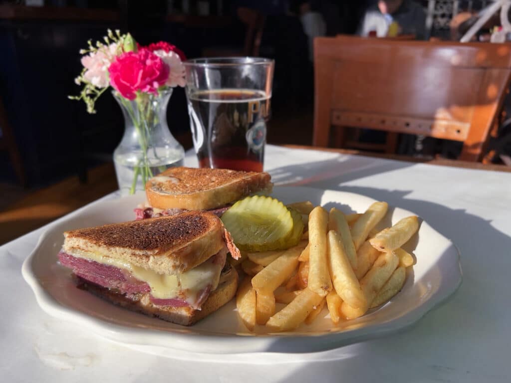 Corned beef reuben sandwich with a side of french fries. 