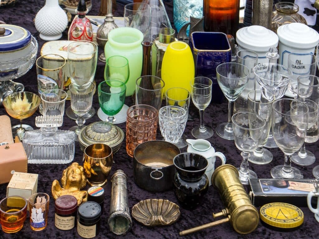 Glassware in various colors on a display table at a flea market.