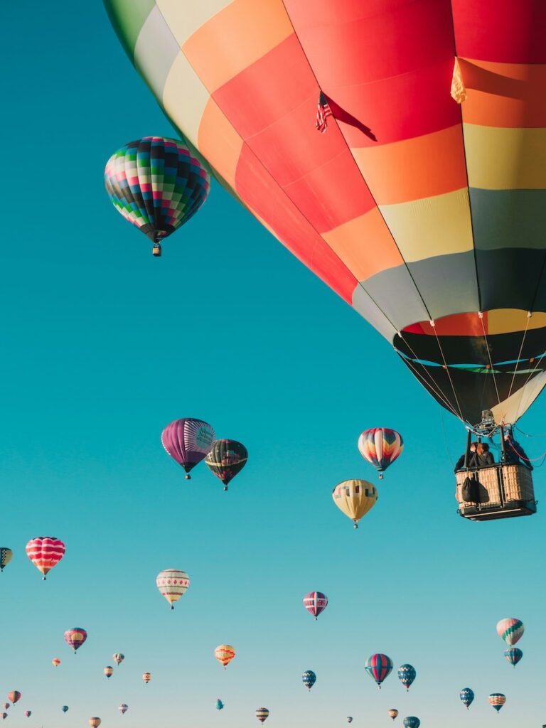 Several colorful hot air balloons flying in a clear blue sky. 
