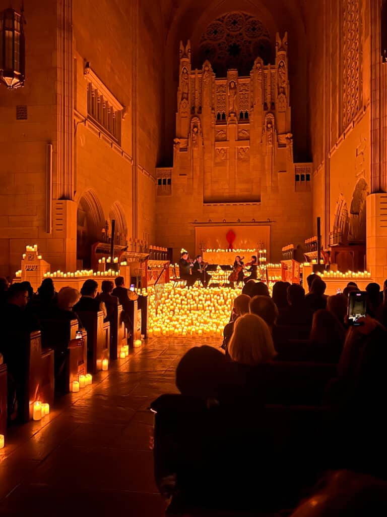 An audience watching a string quartet that is surrounded by LED candles. 